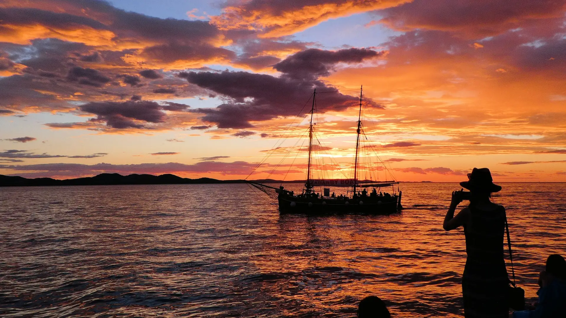 Orange colour sunset sky over water with boat silhouette in Zadar Croatia