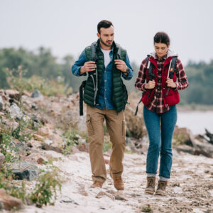 hikers with backpacks walking on sandy beach together