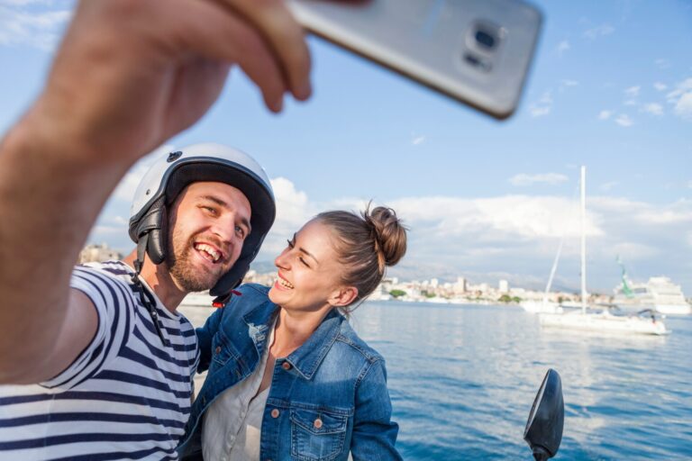 Young moped couple taking selfie on harbour, Split, Dalmatia, Croatia